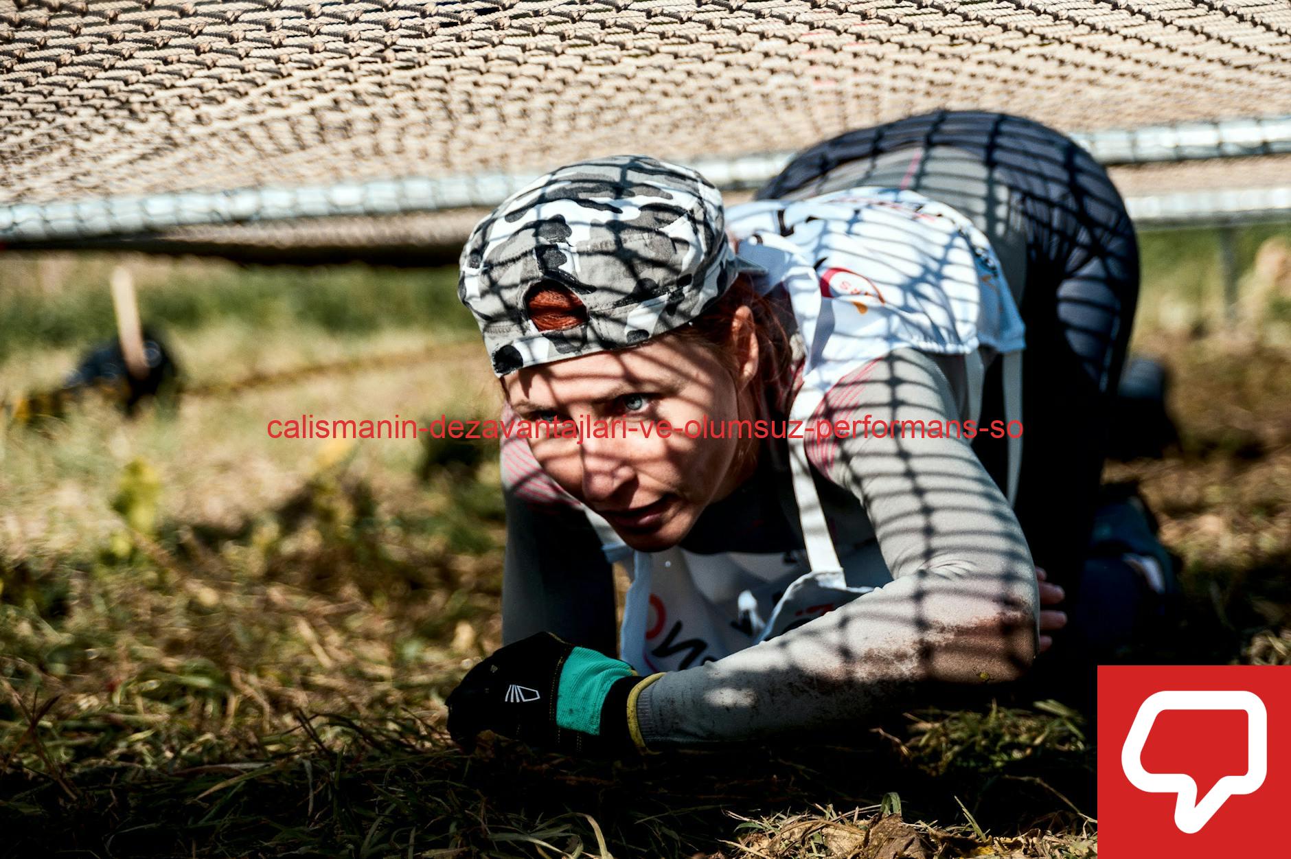 A young woman crawls under a net in an outdoor training or obstacle course.