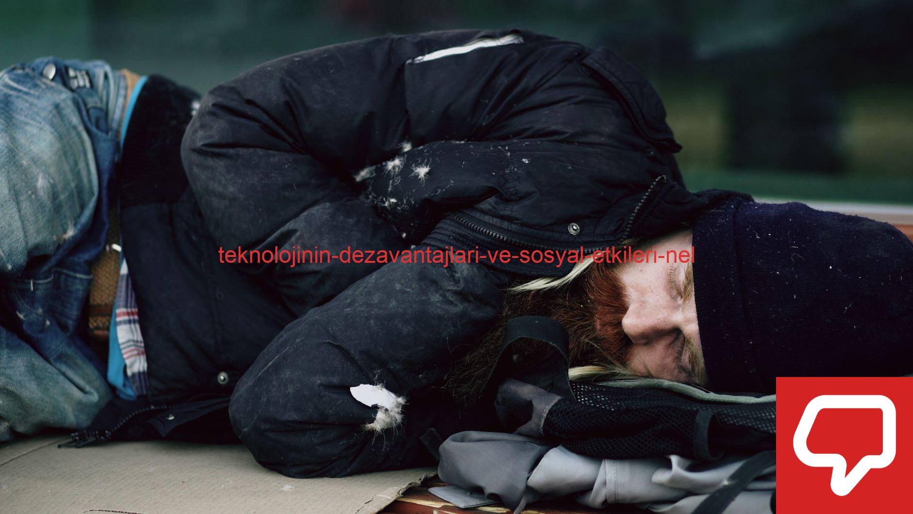 A homeless man sleeping outdoors on cardboard during winter in a city.